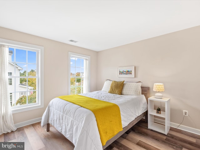 bedroom with multiple windows and dark hardwood / wood-style floors