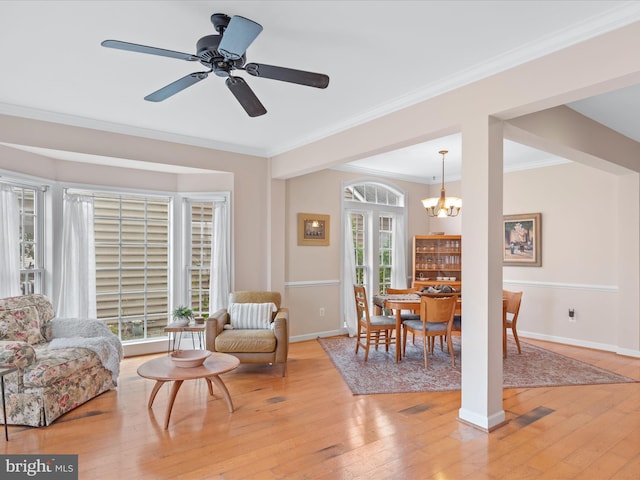 living area featuring ceiling fan with notable chandelier, light hardwood / wood-style floors, and crown molding