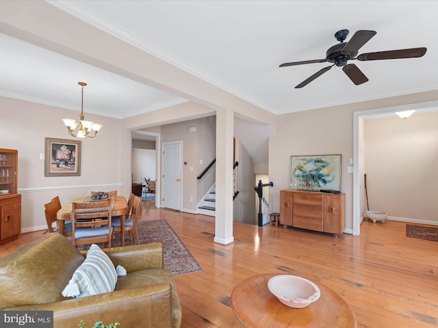 living room featuring ceiling fan with notable chandelier, wood-type flooring, and crown molding