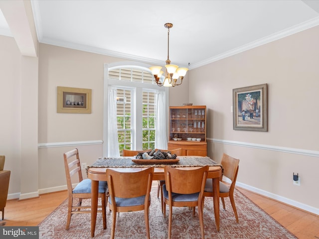 dining area featuring light hardwood / wood-style flooring, ornamental molding, and an inviting chandelier