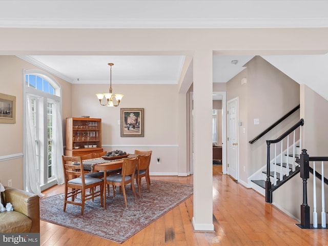 dining area featuring light hardwood / wood-style flooring, a notable chandelier, and crown molding