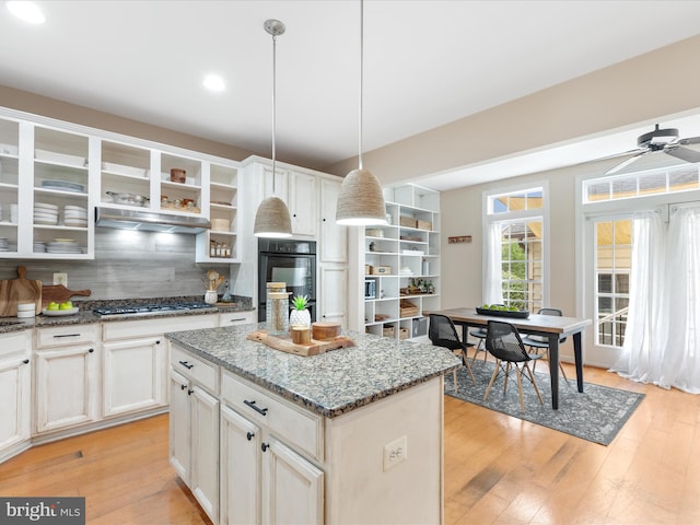 kitchen with ceiling fan, decorative light fixtures, light hardwood / wood-style floors, and a center island