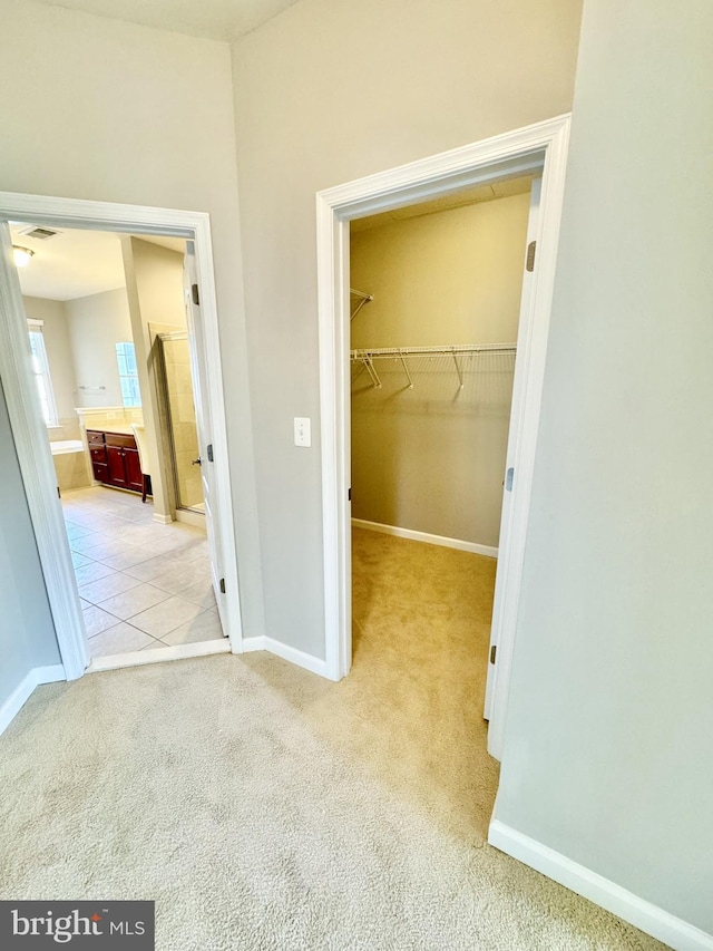 unfurnished bedroom with a walk in closet, a closet, and light carpet