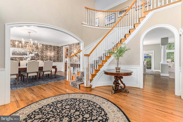 foyer entrance featuring a chandelier, decorative columns, hardwood / wood-style flooring, and crown molding