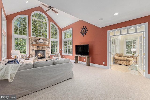 living room featuring ceiling fan, a stone fireplace, light carpet, and a wealth of natural light