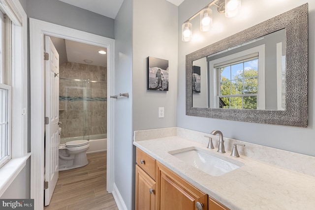 full bathroom featuring wood-type flooring, tiled shower / bath, vanity, and toilet