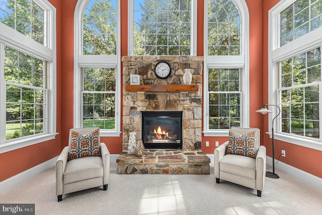 living area with carpet floors, a stone fireplace, and plenty of natural light