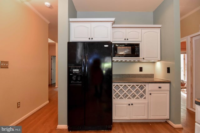 kitchen featuring light wood-type flooring, crown molding, white cabinetry, and black appliances