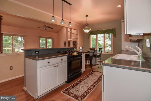 kitchen with wood-type flooring, white cabinets, black stove, and sink