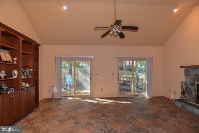 living room with ceiling fan, a stone fireplace, high vaulted ceiling, and a wealth of natural light