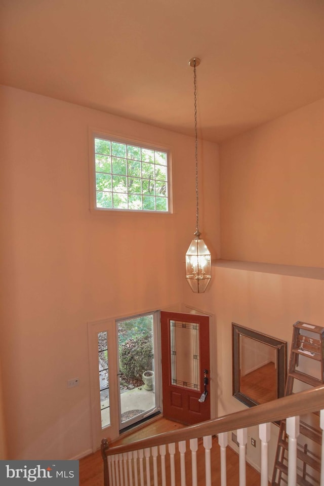 foyer entrance featuring a healthy amount of sunlight, wood-type flooring, and a notable chandelier