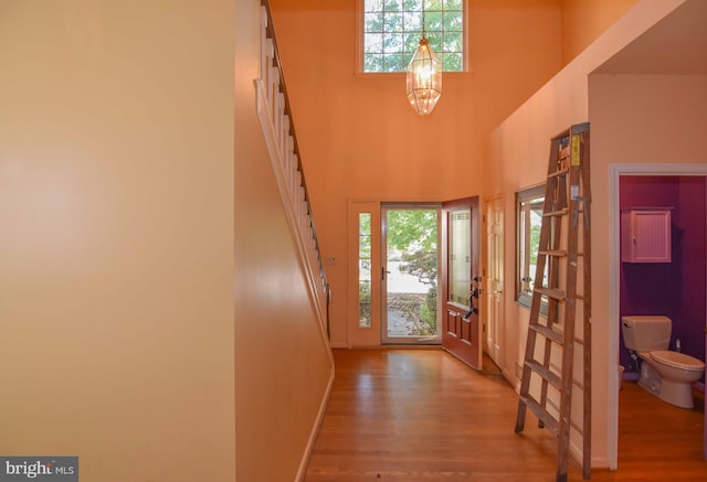 entrance foyer with an inviting chandelier, wood-type flooring, and a towering ceiling