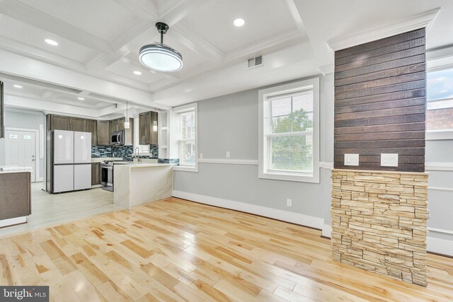 kitchen featuring light stone countertops, stainless steel appliances, a wealth of natural light, and hanging light fixtures