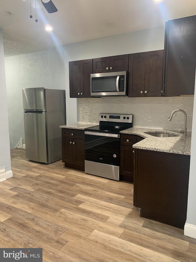 kitchen featuring ceiling fan, stainless steel appliances, dark brown cabinets, and light hardwood / wood-style flooring