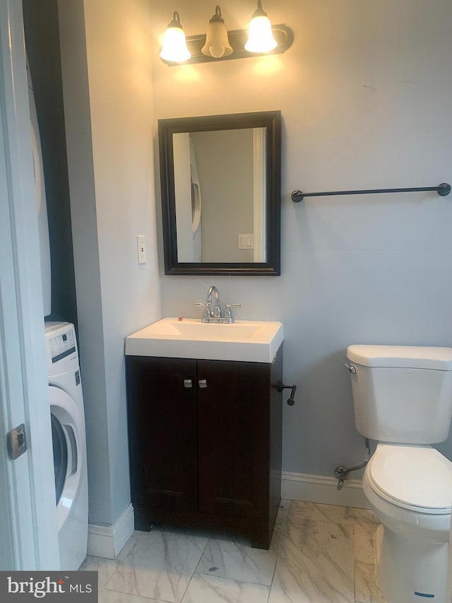 bathroom featuring washer / dryer, vanity, and toilet