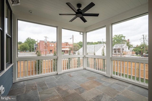 unfurnished sunroom featuring a wealth of natural light, ceiling fan, and wooden ceiling