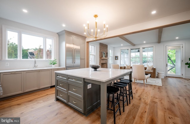 kitchen with stainless steel built in refrigerator, gray cabinets, light hardwood / wood-style floors, a kitchen island, and decorative light fixtures