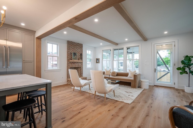 living room featuring a fireplace, plenty of natural light, beam ceiling, and light hardwood / wood-style flooring