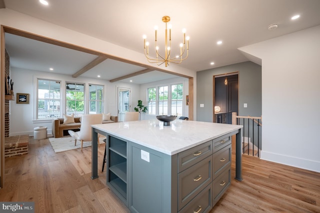 kitchen with light stone countertops, pendant lighting, a center island, light hardwood / wood-style flooring, and a notable chandelier