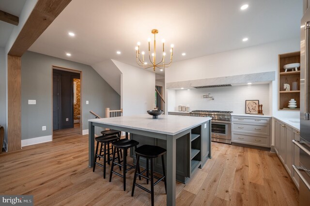 kitchen with decorative light fixtures, a center island, high end stove, a breakfast bar, and light wood-type flooring