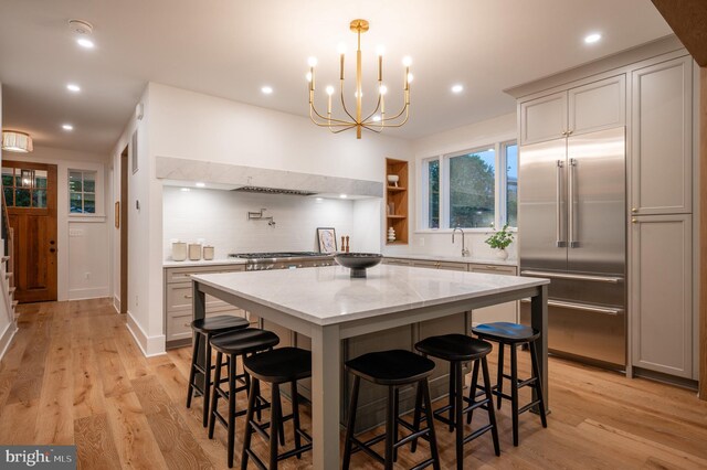 kitchen featuring a breakfast bar, light wood-type flooring, a center island, stainless steel appliances, and light stone countertops