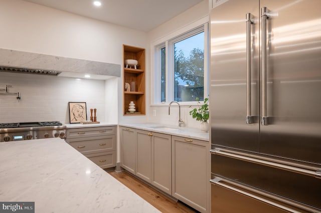 kitchen featuring light stone counters, appliances with stainless steel finishes, sink, and light hardwood / wood-style flooring