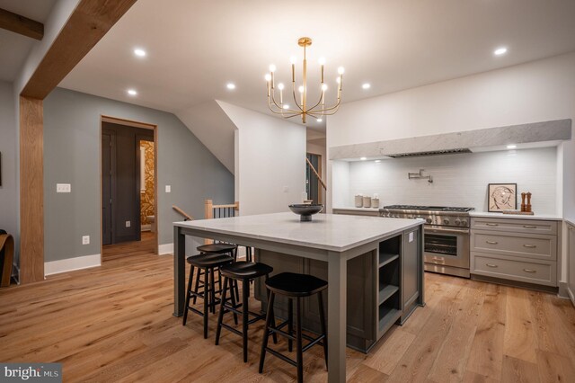 kitchen featuring hanging light fixtures, light hardwood / wood-style flooring, stainless steel stove, gray cabinets, and a center island