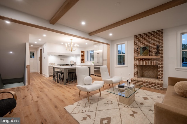 living room with a fireplace, beam ceiling, light hardwood / wood-style flooring, and a chandelier