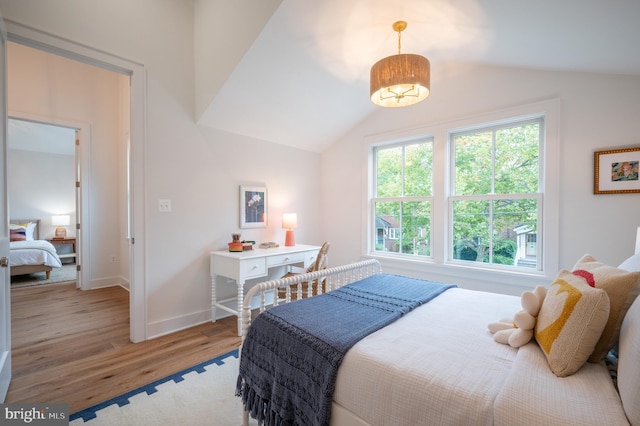 bedroom featuring light wood-type flooring, lofted ceiling, and a chandelier