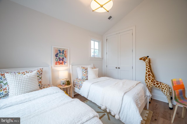 bedroom featuring vaulted ceiling, a closet, and hardwood / wood-style flooring