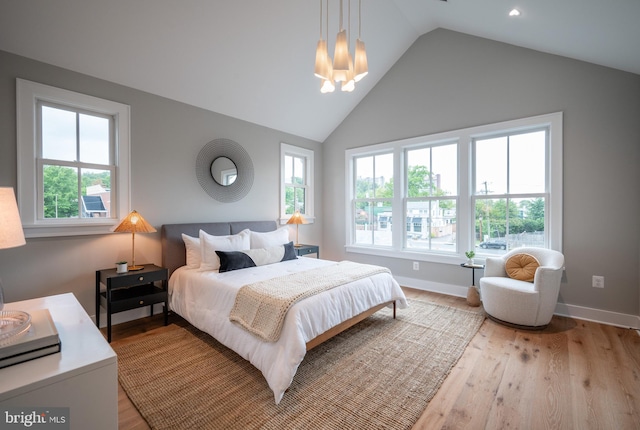 bedroom featuring lofted ceiling, light hardwood / wood-style floors, and a chandelier