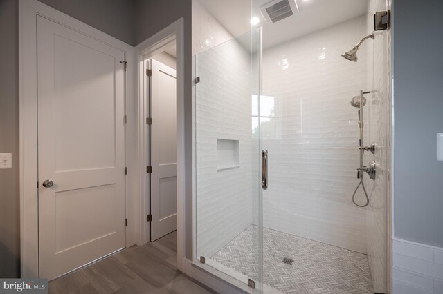 bathroom with hardwood / wood-style flooring and a shower with shower door