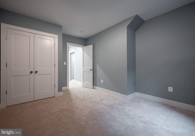 unfurnished bedroom with light colored carpet and a closet