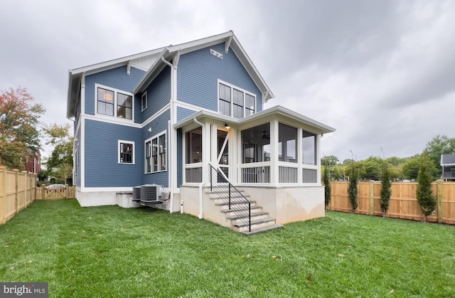 back of house with a sunroom, a yard, and central AC