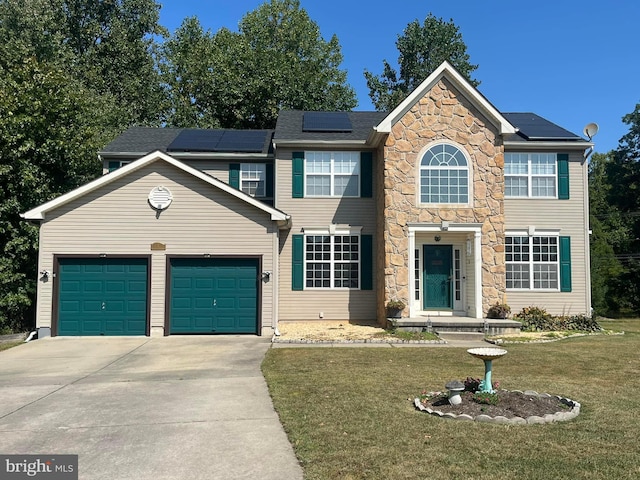 view of front of home with a front yard, solar panels, and a garage