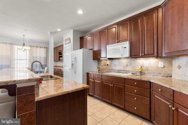 kitchen featuring an island with sink, hanging light fixtures, sink, white appliances, and backsplash