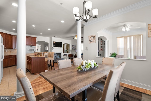 dining area featuring ceiling fan with notable chandelier, sink, light tile patterned floors, and crown molding