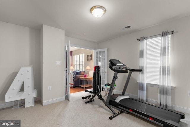 workout room featuring light carpet