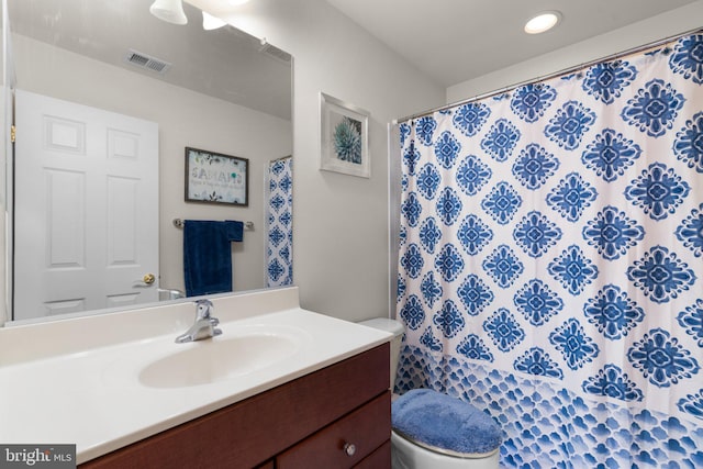 bathroom with walk in shower, vanity, and toilet