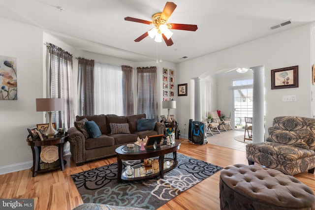 living room with light hardwood / wood-style floors, ceiling fan, and ornate columns