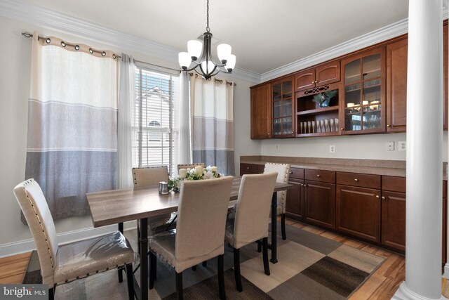 kitchen with an island with sink, light wood-type flooring, ornate columns, and white appliances