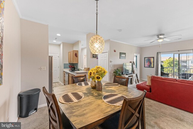 carpeted dining room with ornamental molding and ceiling fan