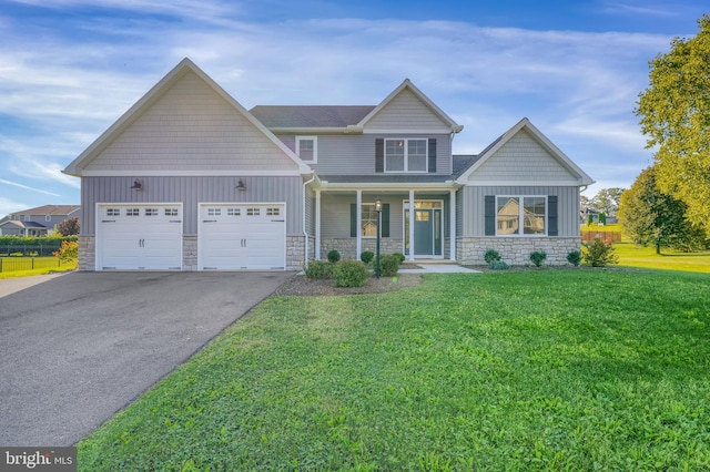 83 Landon Dr, Bellefonte, PA 16823 - craftsman house featuring driveway, stone siding, covered porch, a front yard, and a garage