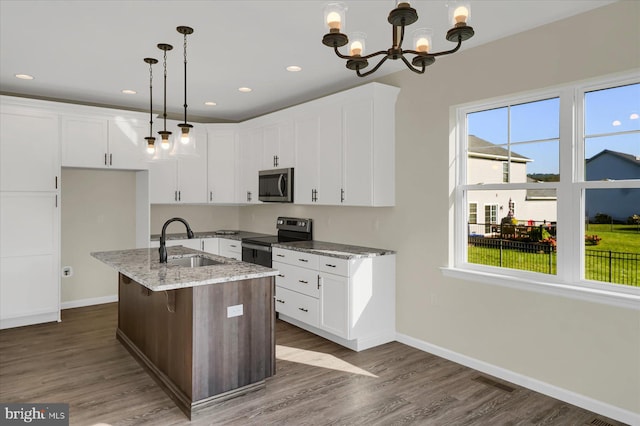 kitchen with sink, pendant lighting, a kitchen island with sink, stainless steel appliances, and light stone counters