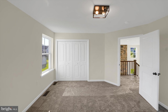 unfurnished bedroom with light colored carpet and a closet