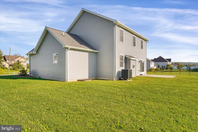 rear view of property featuring cooling unit, a patio area, and a lawn