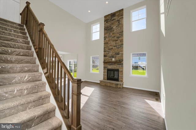 interior space with a fireplace, a towering ceiling, dark hardwood / wood-style floors, and a wealth of natural light