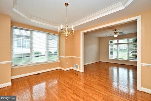 spare room with ceiling fan with notable chandelier, a raised ceiling, wood-type flooring, and crown molding