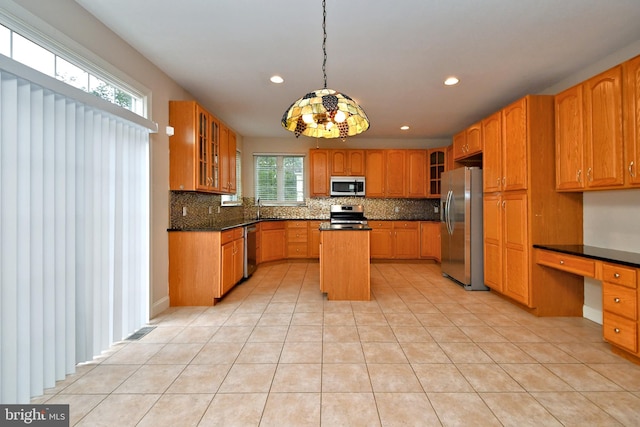 kitchen featuring decorative light fixtures, a center island, backsplash, and appliances with stainless steel finishes