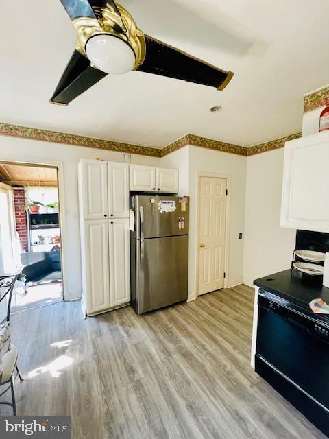 kitchen featuring stainless steel fridge, black electric range oven, white cabinets, and light hardwood / wood-style floors